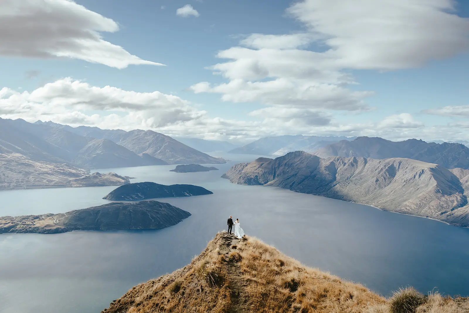 Couple on the Coromandel Peak ridgeline high above Lake Wanaka and its islands