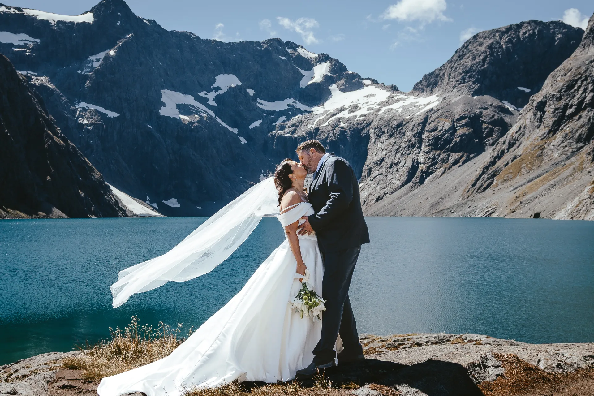 Couple kissing beside a still alpine lake during a Queenstown elopement ceremony